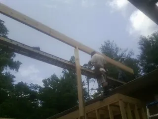 Carpenter setting a ridge beam over a new addition frame — Ice Dam Removal by Roofing Brothers in Mc Clellanville