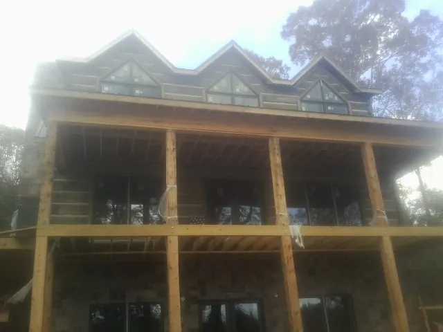 Dormers and porch framing on a large log home under construction — Roof Coating work by our crew in Mc Clellanville