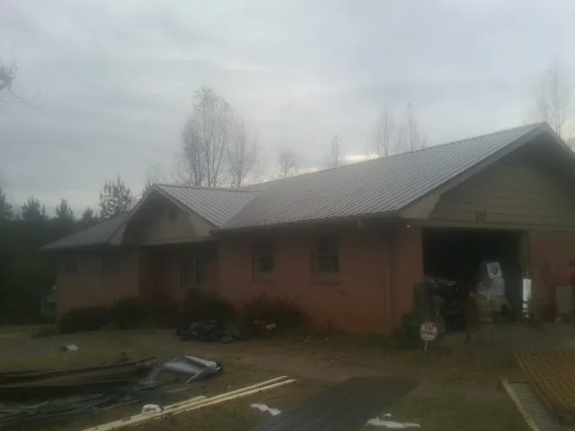 Gray metal roof on a stucco house with an attached garage in Mc Clellanville