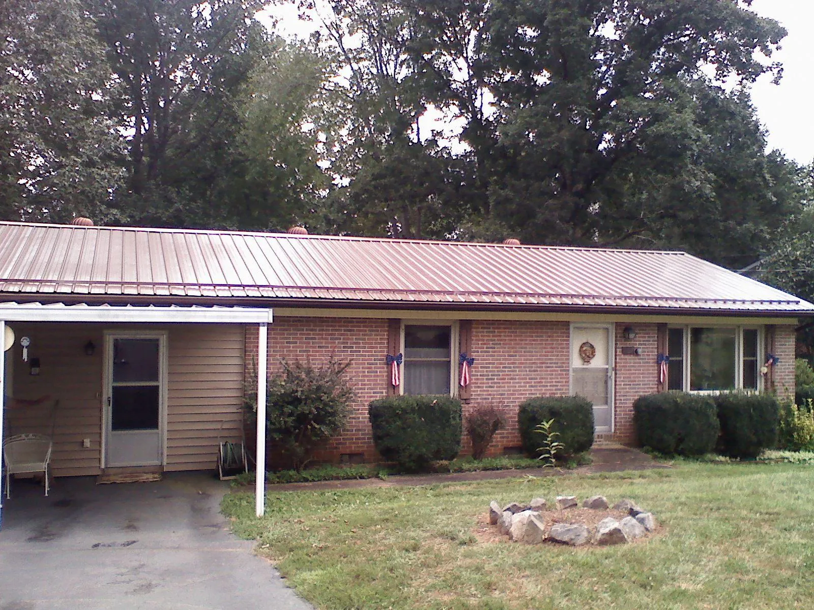 Bronze metal roof and carport on a brick ranch home — Roof Repair work by our crew in Mc Clellanville