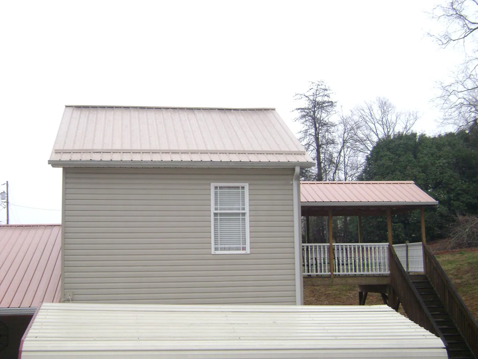 Tan metal roofs on a two story addition and attached porch, from a Roof Replacement job in Mc Clellanville