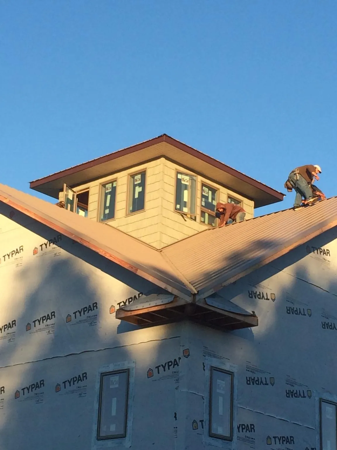 Roofers working around a rooftop cupola on a new metal roof at sunset — Roof Waterproofing in Mc Clellanville by Roofing Brothers